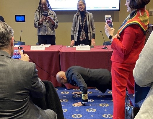 Surgeon General, Jerome Adams is on the ground doing push up in a conference room while people watch and take pictures.